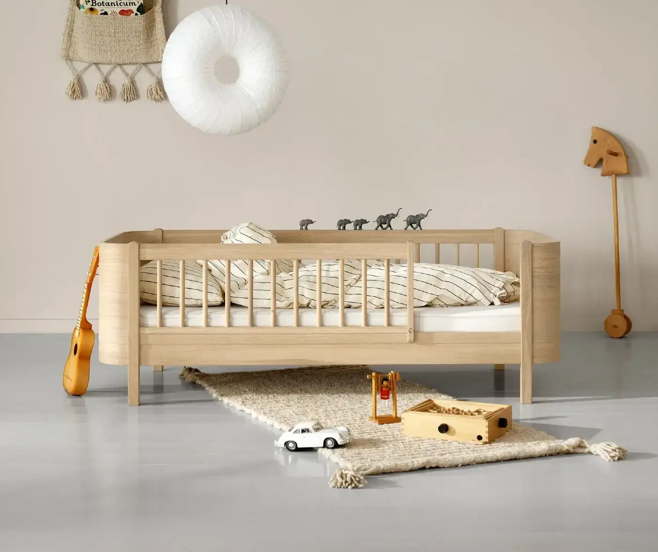 Oliver Furniture Oak Toddler Bed in a Bedroom with rug and toys on floor